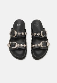 Schwarze Ledersandalen mit zwei breiten Riemen, silbernen Schnallen und dekorativen Nieten, strukturierten Sohlen und Branding auf den Innensohlen.