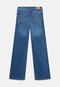 Blå vide denimjeans sett bakfra, med to baklommer og et brunt lærmerke på midjebåndet.