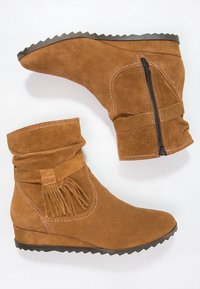Bruine suede wedge enkellaarsjes met een franjerand en een zijkantrits. Getextureerd bovenwerk, ronde neus en rubberen zool met zigzagpatroon.