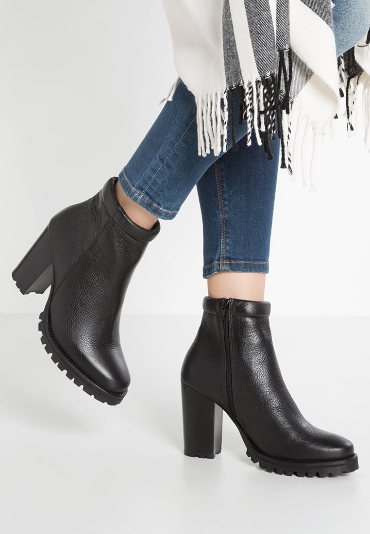 Bottines noires en cuir avec une finition texturée, talon bloc haut et fermeture éclair sur le côté ; semelle extérieure robuste avec un profil prononcé pour une meilleure adhérence.