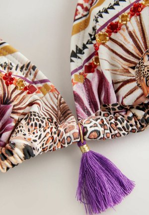 Colorful fabric with animal print and geometric patterns, finished with a purple tassel accent and golden hardware details.