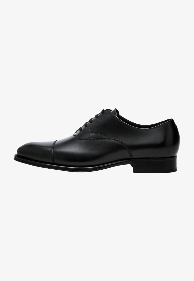 Chaussure habillée Oxford pour homme en cuir noir avec laçage fermé, bout rapporté, et petit talon empilé, vue de profil.