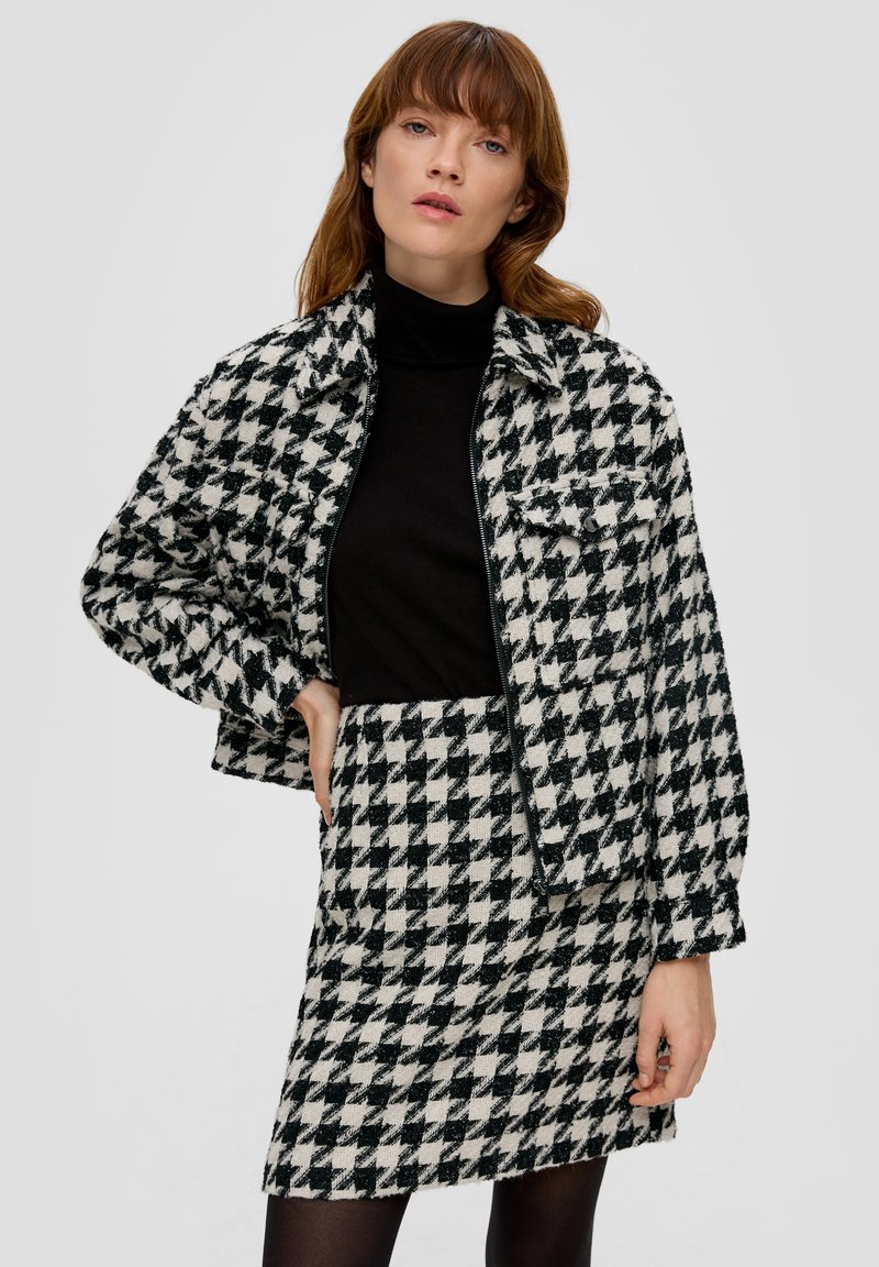 Houndstooth-mustriga lühike jakk ja sobiv seelik mustas ja valges, tekstuuriga viimistlusega ning eest taskud jakil.