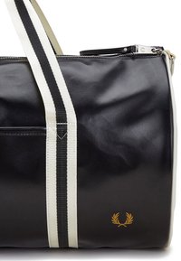 Borsa a duffel nera con tessuto testurizzato, spallacci a strisce bianche e nere, zip argentata e un logo d'oro sul lato.