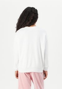 Felpa bianca a maniche lunghe con vestibilità comoda e polsini a coste. Presenta un design semplice con scollatura rotonda.