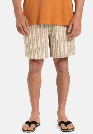 Beige patterned shorts with brown floral stripes. Worn with a rust-colored t-shirt and black flip-flops. Short cut and lightweight fabric.