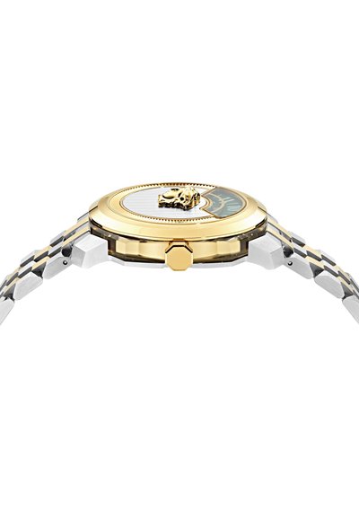 Montre bracelet fine avec un bracelet en métal or et argent, une lunette dorée et un détail en relief représentant une tête de lion dorée près du bord du cadran.