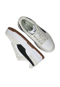 Low-top sneakers with a white leather upper, black suede accents, rubber sole, and perforated design elements for breathability.