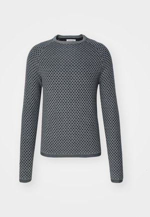 Pull long à manches longues en gris texturé avec un motif en nid d'abeille, encolure ronde et poignets côtelés. Le matériau semble tricoté avec une finition douce.