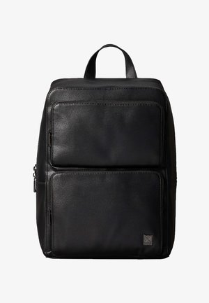 Czarny, teksturowany skórzany plecak z dwoma przednimi kieszeniami na zamek oraz górną rączką, z małą naszywką z logo Calvin Klein na dolnej kieszeni.