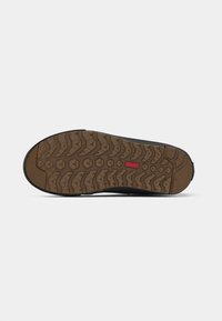 Rubber outsole with a deep tread pattern; brown base with black accents. Features a textured grip for traction and durability.