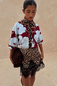 Πουλόβερ με πολλαπλά μοτίβα σε κόκκινο, μπλε και λουλουδάτο σχεδιασμό, συνδυασμένο με φούστα λεοπάρ με μαύρη δαντέλα στο τελείωμα. Αξεσουάρ καφέ τσάντα.