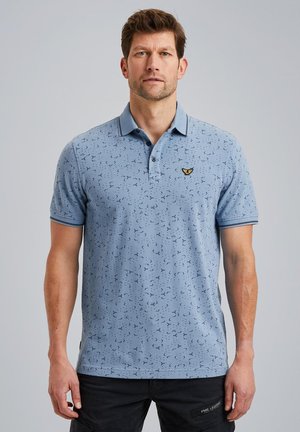 Lysblå polo t-shirt med korte ærmer, med et subtilt mønster og et lille gult logo på venstre bryst.