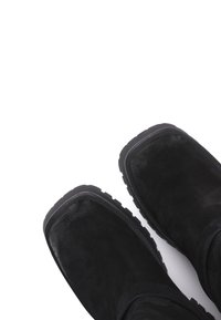 Botine de gleznă din suede negru, cu talpă plată, vârf rotund și finisaj texturat. Design simplu, fără hardware sau accente vizibile.
