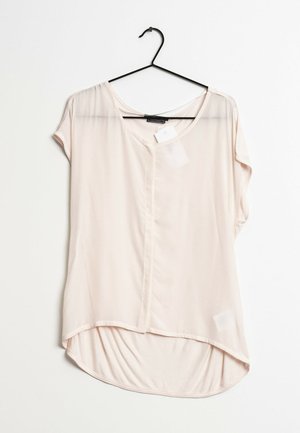 Vaaleanpunainen, lyhythihainen pusero, jossa on pyöreä pääntie, edessä napitus ja kaareva helma. Valmistettu sileästä, kevyestä kankaasta.