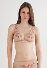 Nude beha met bloemenborduursel in roze en blauw, met een diepe V-hals en verstelbare bandjes, gemaakt van een lichte, doorzichtige stof.