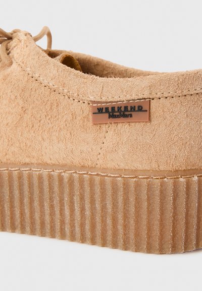 Beige mockaskor med en texturerad, ribbad beige sula. Har en "WEEKEND MaxMara"-logotyp på en liten läderetikett. Snörning upptill.