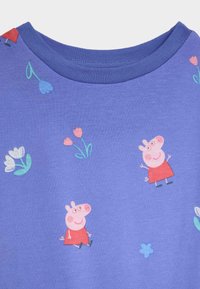 Paarse katoenen T-shirt met een ronde halslijn en een herhalend patroon van cartoonvarkens en bloemen in roze en blauwe tinten.