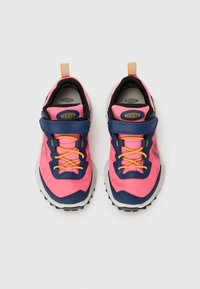 Bunte Sportschuhe mit einem pinkfarbenen Mesh-Obermaterial, marineblauen Akzenten, gelben Schnürsenkeln und einer robusten schwarzen Außensohle. Klettverschluss für sicheren Sitz.