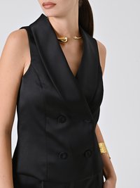 Gilet satinato nero doppiopetto con scollatura a V profonda, caratterizzato da bottoni rotondi e una texture liscia. Accenti di collana e bracciale in oro.