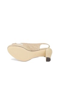 Sandalo con tacco in beige a effetto slouch, con tomaia in tessuto testurizzato decorata con strass, punta aperta e design con cinturino posteriore. Suola in gomma piatta.