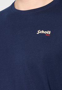 Marineblaue Kurzarm-T-Shirt aus Baumwolle mit rundem Halsausschnitt und kleinem gesticktem Logo in Beige und Rot auf der Brust.