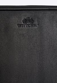 Portfolio in pelle nera con superficie texturizzata. Presenta il logo "WITTCHEN" impresso nella parte superiore e una chiusura con zip lungo il bordo.