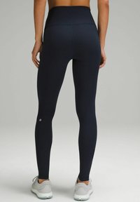Hoch taillierte marineblaue Leggings aus dehnbarem Material. Sie verfügen über ein enganliegendes Design mit einem Logo-Detail nahe dem Knöchel und flachen Nähten für zusätzlichen Komfort.