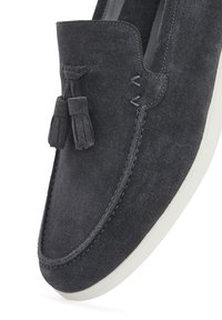Suede loafers in dark gray feature a rounded toe, stitched detailing, and two tassels on the vamp. Contrasting white sole for added style.