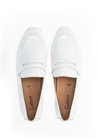 Weiße Lederloafers mit glatter Oberfläche, abgerundeter Zehenpartie, dekorativer Naht und gepolstertem Fußbett. Markenlogo sichtbar im Inneren.