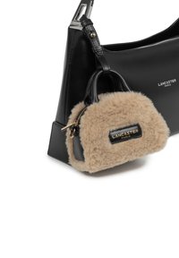 Borsa a tracolla nera in pelle con una mini borsa fluffy beige staccabile, dotata di zip e una toppa con logo embossato in oro sul davanti.