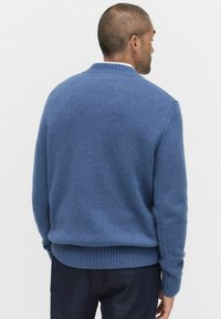 Niebieski sweter dzianinowy z teksturowanej tkaniny, z prążkowanymi mankietami i dołem. Prosty fason z okrągłym dekoltem, widok z tyłu.