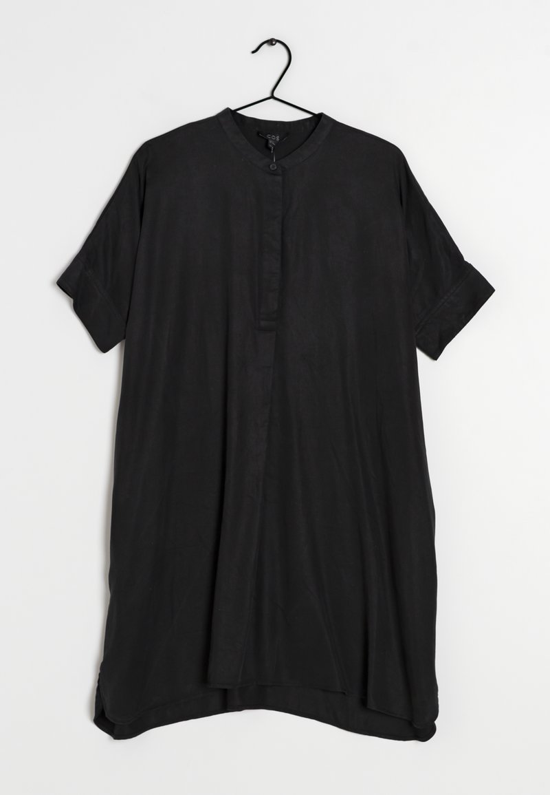Robe noire en tissu lisse, dotée d'un col montant, de manches courtes et d'une coupe décontractée avec un ourlet légèrement arrondi.