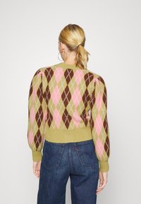 Stickad tröja med puffärmar som har ett flerfärgat argyle-mönster i rosa, brunt och grönt. Ribbad nederkant och rund halsringning.