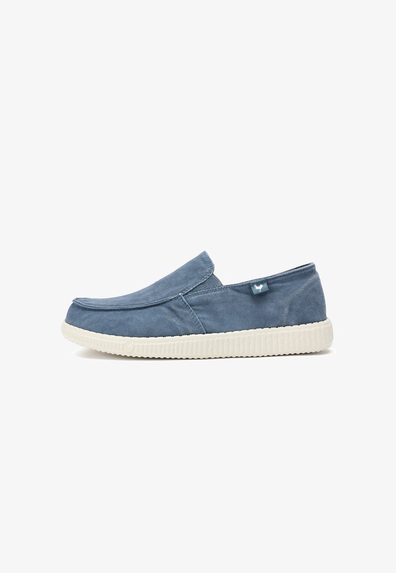 Chaussure décontractée slip-on en tissu bleu avec semelle en caoutchouc blanche et petite étiquette latérale, présentée de profil sur fond blanc.
