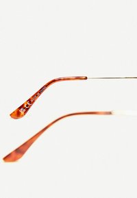 Rámy okuliarov s korytnačím vzorom s lesklým povrchom, vybavené kovovými akcentmi a gravírovanými detailmi, skosené pre pohodlie a štýl.