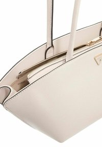 Borsa tote beige con texture e dettagli neri, dotata di due lunghe tracolle e una chiusura con zip dorata, che presenta un logo sul lato.