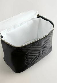 Borsa sintetica nera trapuntata con zip nella parte superiore; interno foderato in bianco. Presenta un design embossato all'esterno. Forma compatta.
