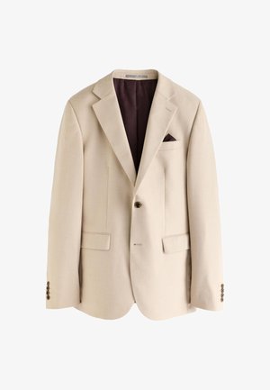 Blazer beige simple boutonnage avec revers crantés, un bouton, deux poches avant à rabat, une poche poitrine avec un mouchoir de poche marron foncé et une doublure marron foncé.