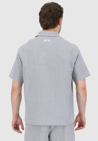 Short-sleeve shirt in blue and white vertical stripes. Collared design with a label at the back. Soft, lightweight fabric and loose fit.