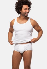 Witte geribbelde tanktop en onderbroek op een gespierde man, die een slim fit ontwerp, gladde textuur en elastische tailleband benadrukt.