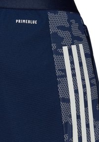 Marineblauwe sportshorts van Primeblue-materiaal, met een gestructureerd oppervlak, hexagonaal patroon en drie witte strepen aan de zijkant.