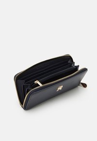 Marineblaues Lederportemonnaie mit goldenen Reißverschluss und Beschlägen. Das Innere bietet mehrere Fächer und Kartensteckplätze und zeigt ein schickes Design.
