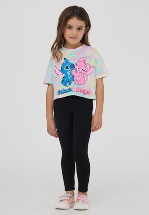 T-shirt corta in stile uncinetto con un motivo multicolore pastello che presenta i personaggi dei cartoni animati Stitch e Angel; abbinata a leggings neri.