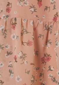 Květinová tkanina se světle růžovým pozadím a malými bílými a červenými květinami. Měkká, lehká textura s nabíranými detaily.