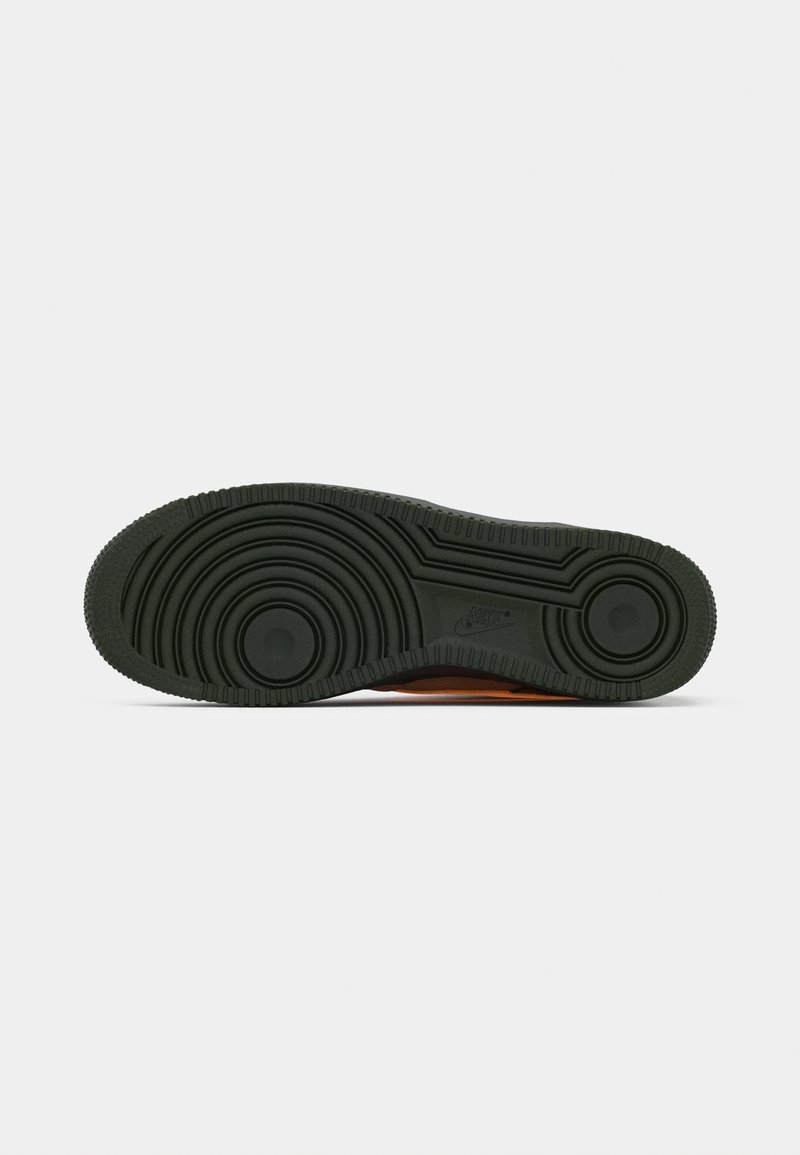 Semelle de chaussure Nike montrant un matériau en caoutchouc noir ; présente des motifs circulaires, des lignes de grip texturées et un logo bien en vue.