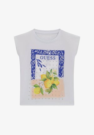 Maglietta bianca senza maniche con cornice ornamentale blu, scritta "GUESS" e un mazzo di limoni gialli con foglie verdi sul davanti.