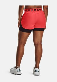 Pantalones cortos deportivos rojos y negros con cintura elástica. Tejido ligero y transpirable con un diseño en capas que presenta un forro negro debajo.