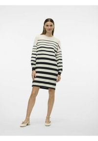 Abito a maglia a righe in crema e nero. Vestibilità comoda, maniche lunghe, collo a giro e lunghezza al centro coscia. Texture liscia con righe orizzontali.