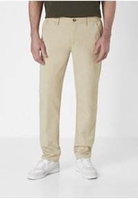 Beige cotton trousers with a straight leg design, featuring a button closure and side pockets, paired with white sneakers.